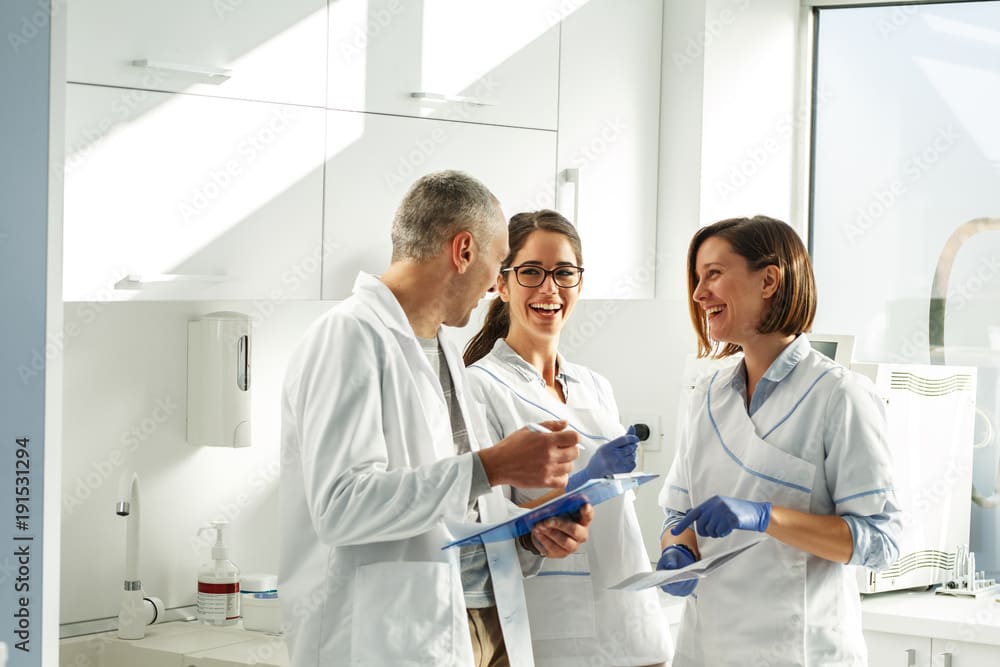 Medical dentist team in dental office discuss about practice and examining list of patients.