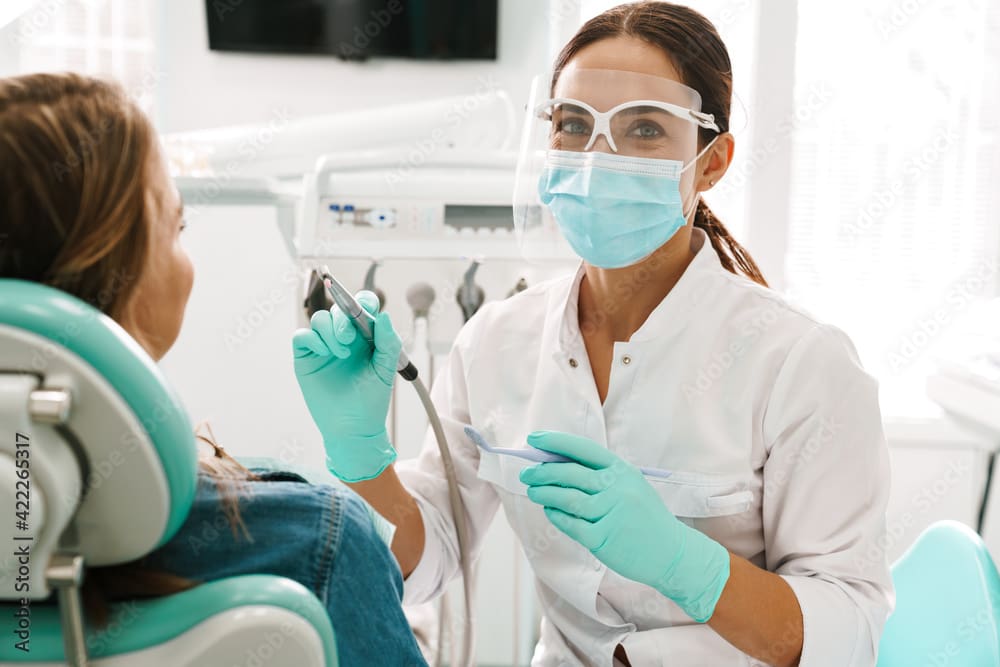 European mid dentist woman in face mask working in dental clinic